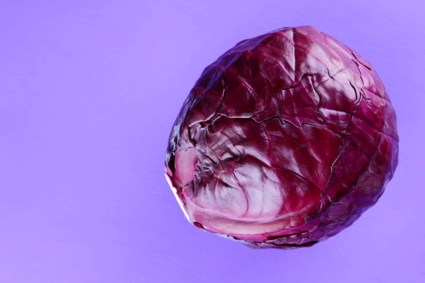 Red cabbage on a purple background, vegetarian food, cabbage for a designer, copy space, top view, minimalist vegetables, pop art, ultraviolet - Photo, image