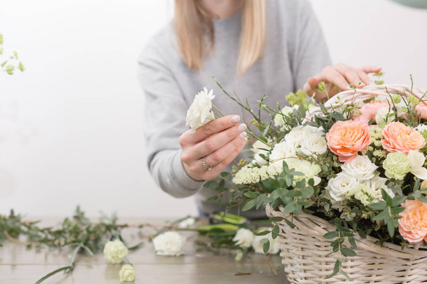 yakın çekim yakışıklı kadın çiçekçi. Çiçek atölye - kadın güzel çiçek kompozisyon bir buket bir hasır sepet yapım. Floristik kavramı - Fotoğraf, Görsel