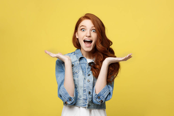 Lifestyle Concept: Smiling beautiful young woman in jean clothes posing with hands on chin. Isolated over yellow background. - Photo, Image
