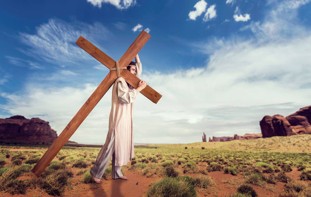 großer Märtyrer mit Kreuz in der Wüste, bewölkter Himmel mit Sonnenstrahlen, Kreuzigung des Jesus Christus - Foto, Bild
