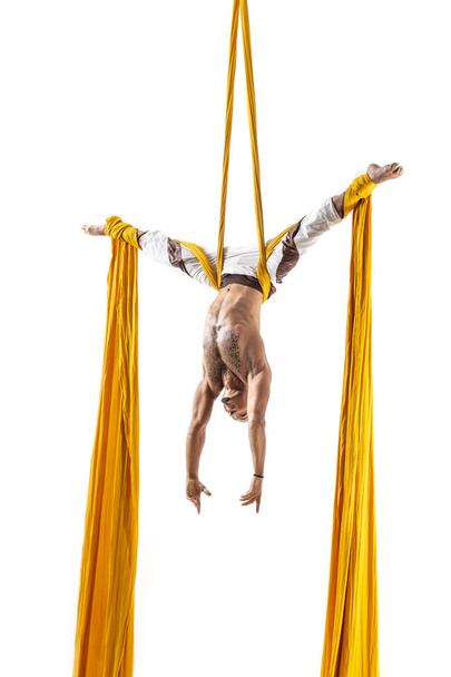 привабливий м'язистий чоловік робить акробатичне виконання з жовтими тканинами на білому тлі
 - Фото, зображення