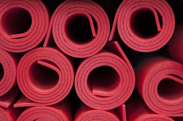 Lote de tapetes de fitness de espuma roja enrollada fondo
 - Foto, Imagen