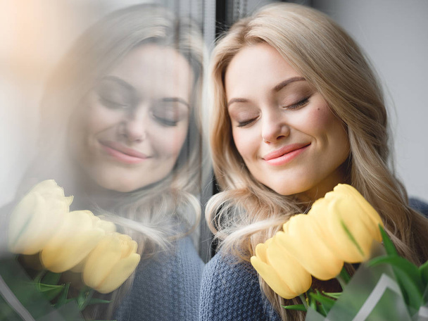 Glad young woman enjoying smell of tulips - Photo, Image