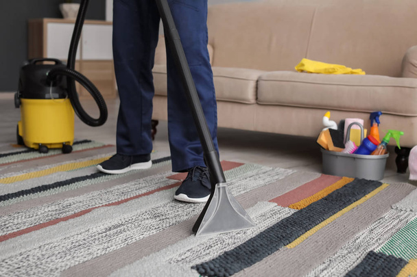 Mature man hoovering carpet with vacuum cleaner in living room - 写真・画像