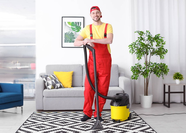 Mature man hoovering carpet with vacuum cleaner in living room - 写真・画像