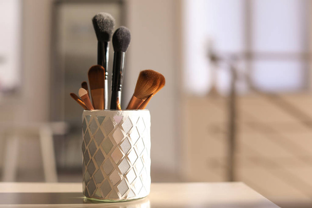 Holder with makeup brushes on table - 写真・画像