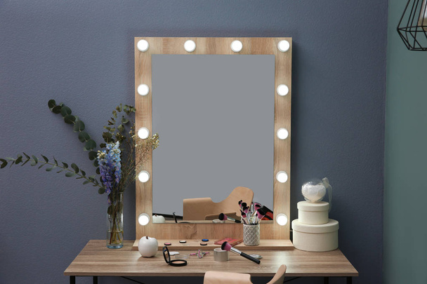 Table with beautiful mirror and cosmetics in modern makeup room - Photo, Image