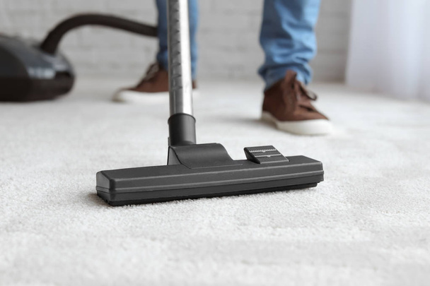 Man cleaning carpet with vacuum at home - Foto, Bild