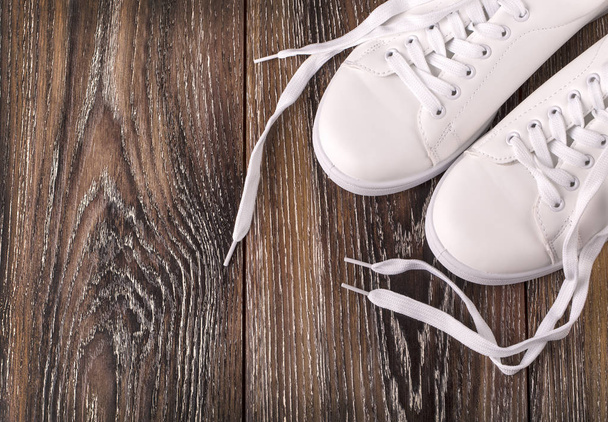 weiße Turnschuhe auf dunkler Holzoberfläche. Schuhe für Frauen im Sport  - Foto, Bild