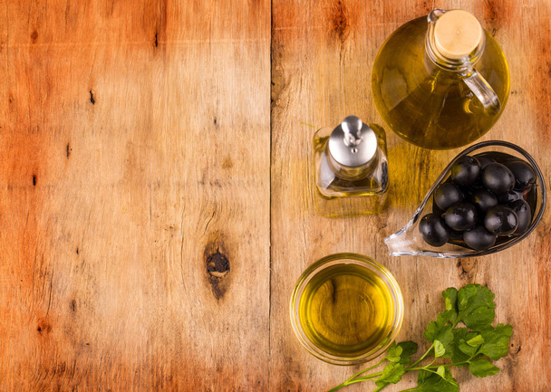 Olio di oliva con erbe fresche e olive nere su legno
 - Foto, immagini