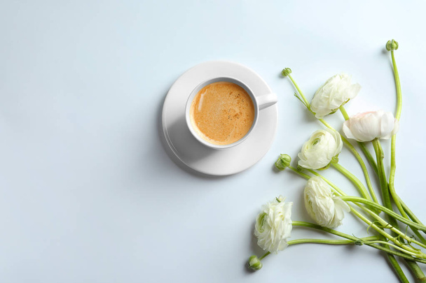Cup of hot coffee and beautiful ranunculus flowers on white background - Foto, imagen