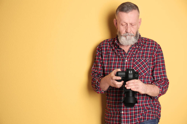 Mature male photographer with camera on color background - Foto, afbeelding