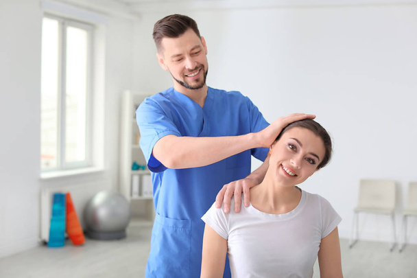 Physiotherapist working with female patient in clinic - Фото, зображення