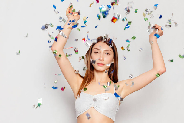 brunette woman with long hair smiling and confetti falls everywhere. - Foto, Bild