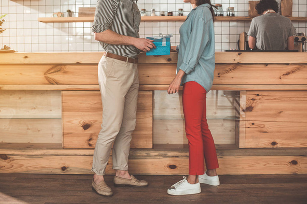 Young man giving present to woman in coffee shop - Фото, зображення