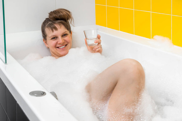 Красивая молодая женщина принимает расслабляющую ванну с пеной
 - Фото, изображение