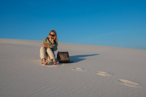 Serious young woman uses tablet in desert - Фото, изображение