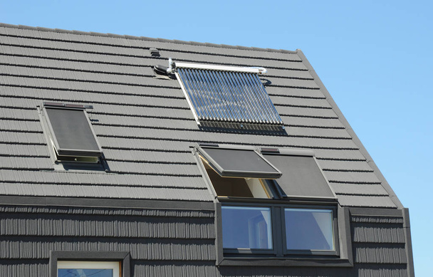 Modernes Dachgeschoss-Dach mit Sonnenkollektoren, Oberlichtern und Jalousien Fenster für Sonnenschutz und Energieeffizienz des Hauses. - Foto, Bild