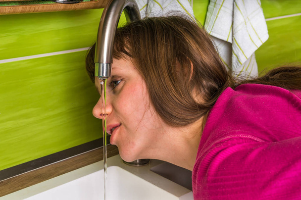 Приваблива жінка п'є прісну воду з крана
 - Фото, зображення