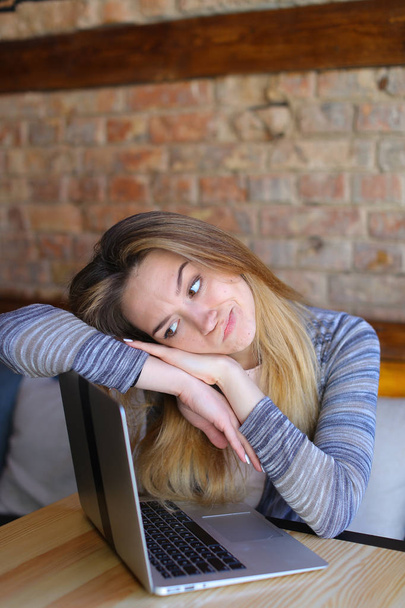 Θλιβερή φοιτήτριας στον ύπνο κοντά σε φορητό υπολογιστή στο café. - Φωτογραφία, εικόνα