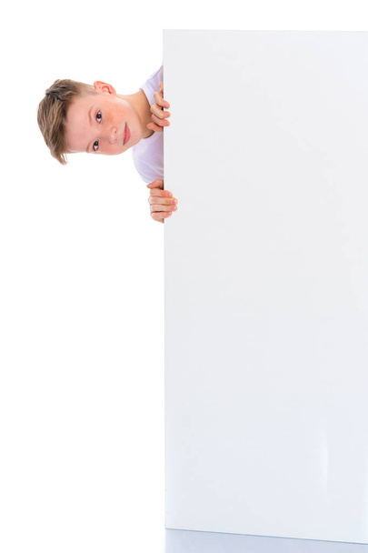 A boy of school age near a white advertising banner. - Фото, изображение