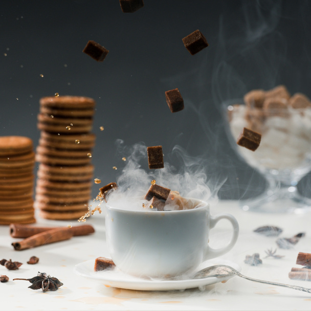 Close-up of brown sugar cubes falling into coffee cup with splashes - Photo, Image