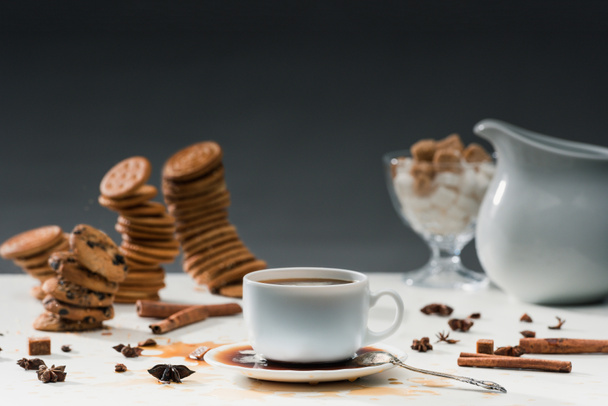 Cup with spilled coffee on table with biscuits and spices - Foto, Imagem