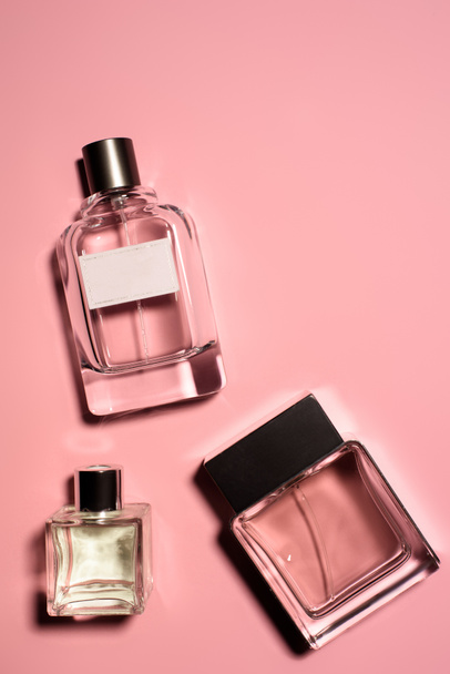 top view of bottles of various of perfumes on pink surface - Fotó, kép