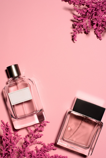 top view of bottles of perfumes with pink branches on pink surface - Photo, Image