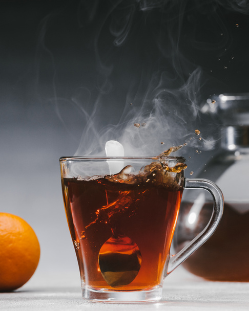 Mélange de thé noir avec cuillère dans une tasse en verre
 - Photo, image