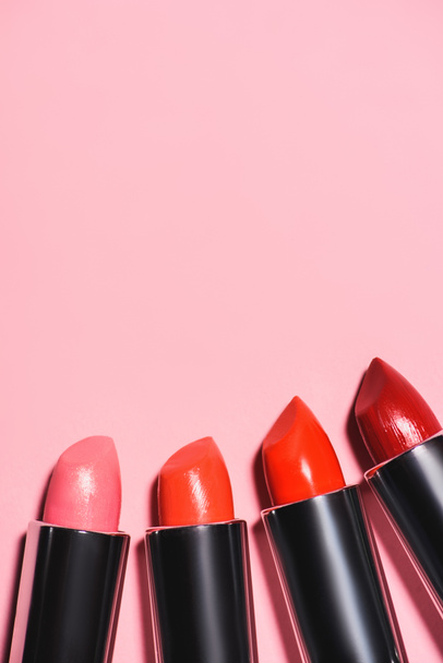 top view of different lipsticks on pink surface - Fotó, kép