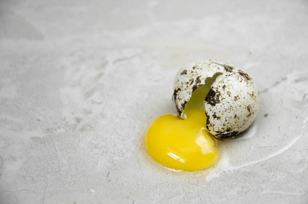 quail egg, crashed on the gray floor bright yolk - Photo, image