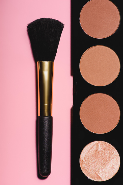 top view of bronzer palette with brush on pink surface - 写真・画像