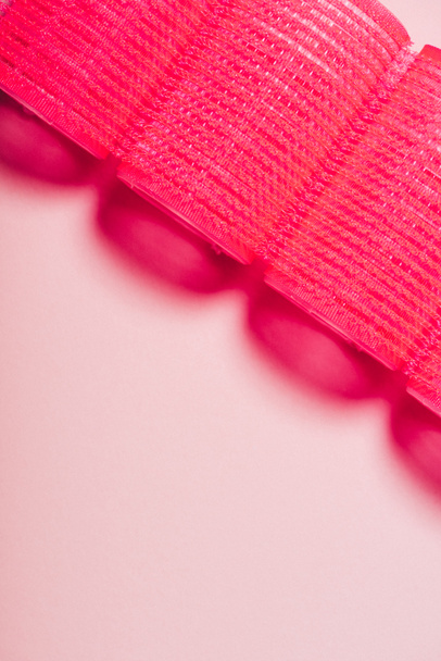 vista superior de rizadores de pelo rojo en fila en la superficie rosa
 - Foto, Imagen