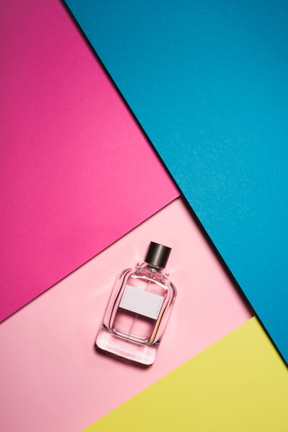 κάτοψη του γυαλί μπουκάλι άρωμα στην πολύχρωμη επιφάνεια - Φωτογραφία, εικόνα