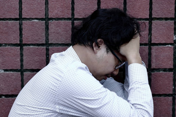 Primer plano frustrado estresado asiático hombre de negocios en la depresión con las manos en la frente
 - Foto, Imagen