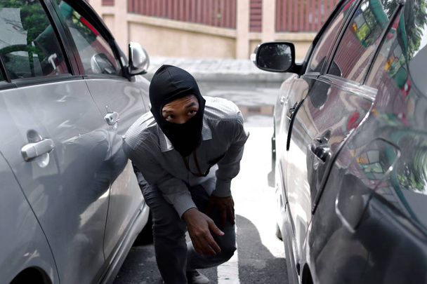 Thief in black balaclava trying to break into car - Photo, Image
