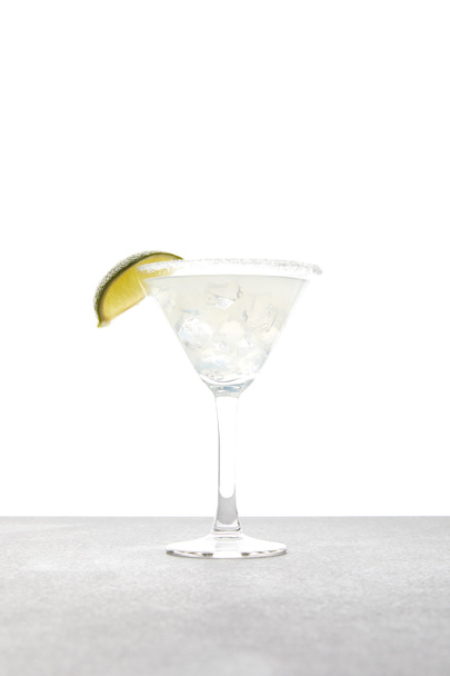 Close-up van verfrissende alcohol margarita cocktail met limoen en ijs op tafelblad op wit - Foto, afbeelding