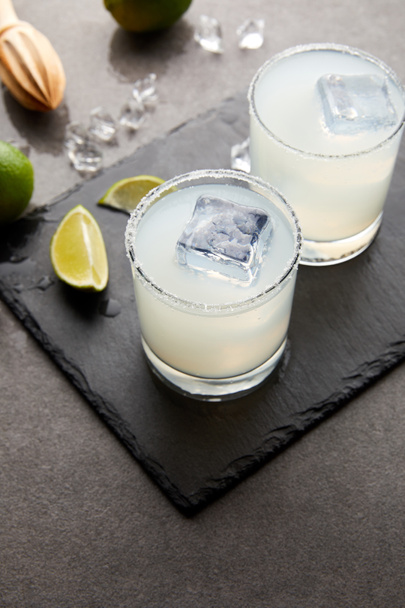 vista ravvicinata di spremiagrumi in legno, rinfrescanti cocktail di caipirinha acida con calce e ghiaccio sul tavolo grigio
 - Foto, immagini