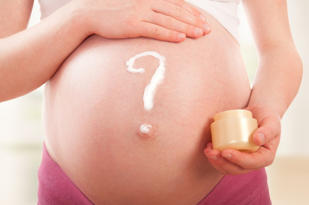 Vientre de la mujer embarazada y signo de interrogación, crema pintada
 - Foto, Imagen
