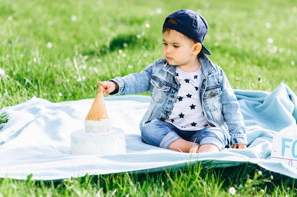 Cute little boy celebrating a birthday, eating blue cake outdoors - Фото, зображення
