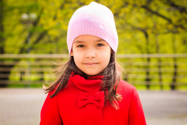 cute smiling girl in pink hat in red coat looking at camera - Photo, image