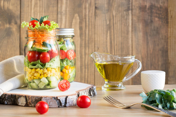 Vegetable healthy homemade colorful salad in mason jar with tomato, lettuce, broccoli on wooden board. Copy space. Lunch for work. - Фото, зображення