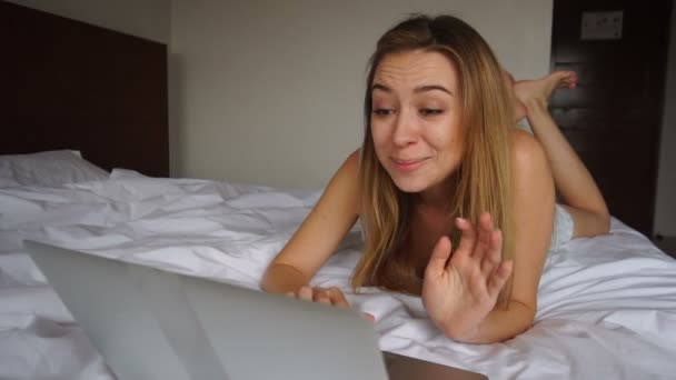 Jocund girl winning bet online by laptop and lying in white quilt at hotel. - Felvétel, videó