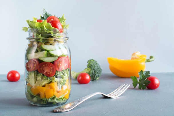 Vegetable healthy homemade colorful salad in mason jar with tomato, lettuce, broccoli on blue. Copy space. Lunch for work. Food set. - Fotoğraf, Görsel