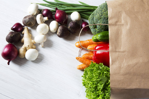 Paper bag of different vegetables on wooden background. Healthy food. Top view. From above. Copy space. - Photo, Image