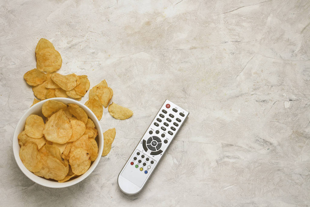 Remote from the TV, Bowl with Chips on a Light Stone Background. - Foto, Imagem