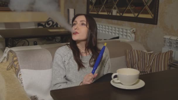 Młoda kobieta w kawiarni palenia fajki - Materiał filmowy, wideo