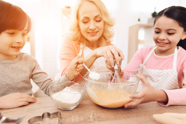 Grandmother teaching grandchildren cooking pancakes at kitchen - 写真・画像