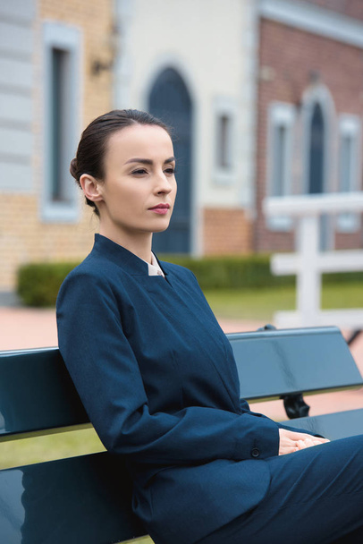 beautiful businesswoman sitting on bench in city and looking away - 写真・画像